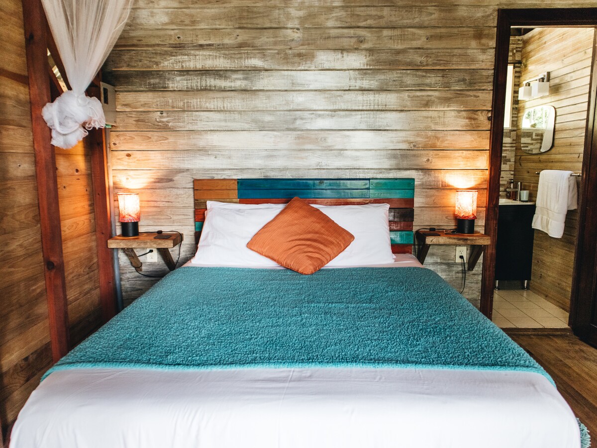 Queen bed inside the rustic wood Tree Cabin at SurfBreak at Paunch